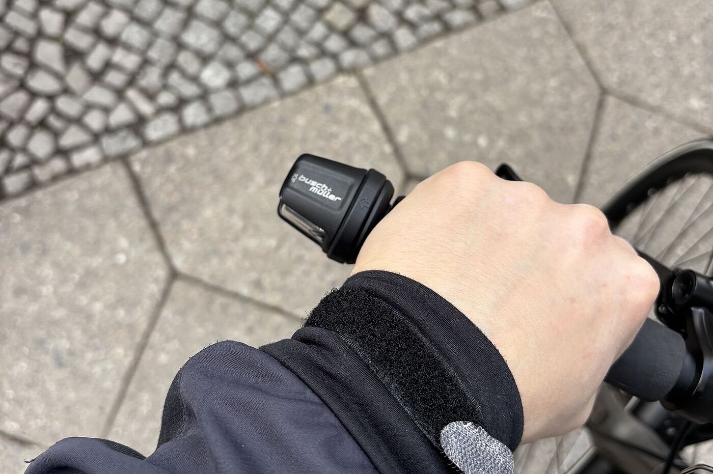 Eine Hand am Fahrradgriff, daneben ein Fahrradblinker. 